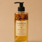 HerYang Oshun Honey Hydrating Body Oil with warm vanilla and citrus scent, shown in a clear glass bottle with a pump dispenser.